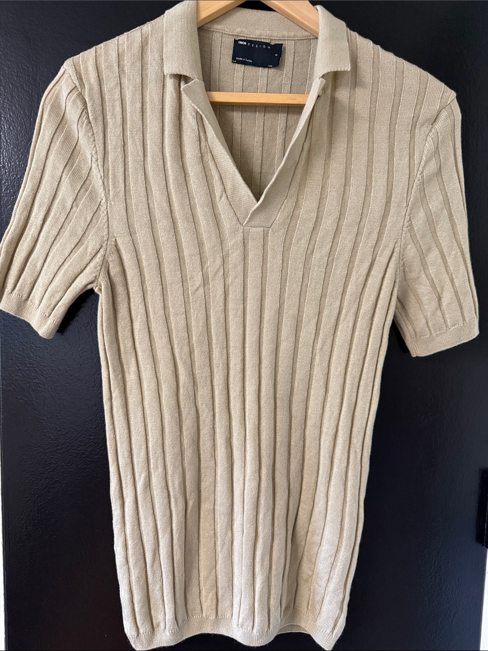 vertically ribbed knit texture and a wide, open V-neck collar.